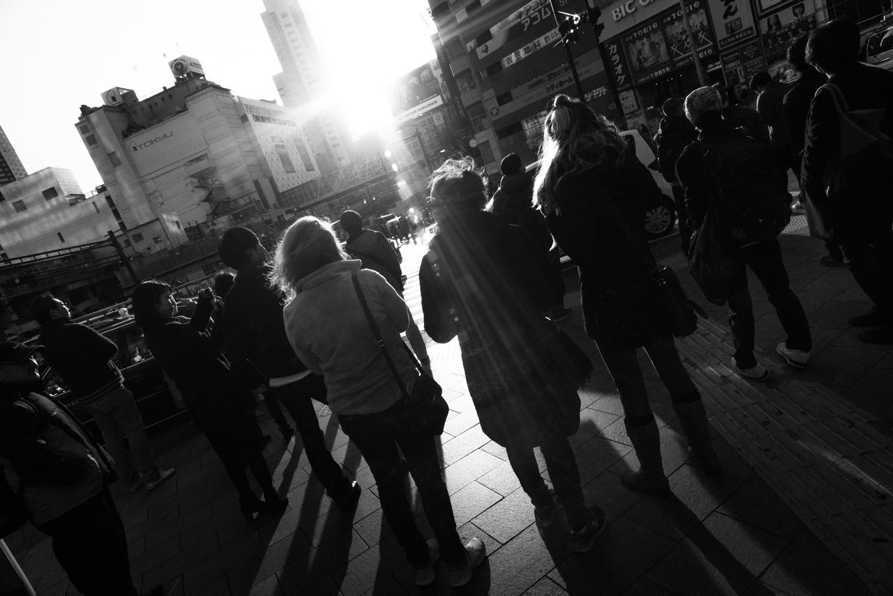 group of people, architecture, building exterior, city, built structure, real people, street, men, city life, women, large group of people, group, adult, crowd, walking, day, lifestyles, leisure activity, outdoors, lens flare