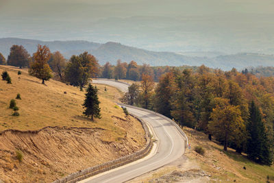 Road amidst trees against sky during autumn