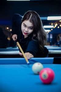 Portrait of young woman playing pool