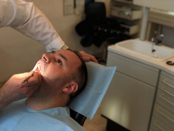 High angle view of dentist examining man