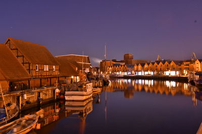 Reflection of illuminated buildings in lake against sky at night