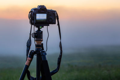 Professional black dslr camera on tripod shooting landscape dawn close up with selective focus