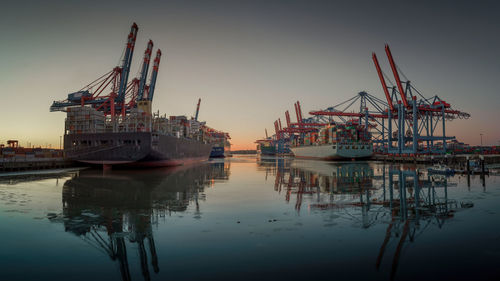 Cranes at commercial dock against sky