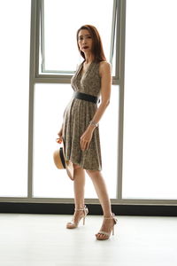 Portrait of beautiful woman standing against window