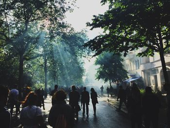 People on street amidst trees against sky