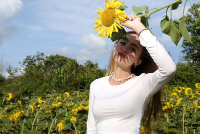 Portrait of a smiling young woman standing against yellow flowering plants