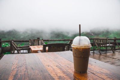 Iced coffee in disposable cup on table against sky
