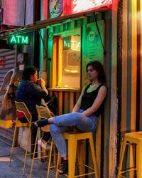 Woman sitting on table at illuminated restaurant