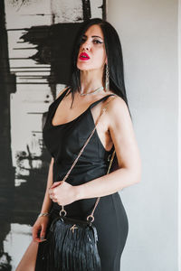 Portrait of young woman standing against wall