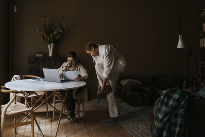 Non-binary person wearing socks by friend analyzing bills at home