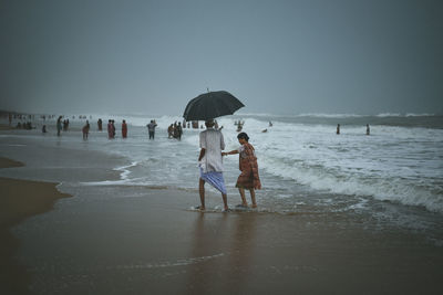 People walking on beach against clear sky