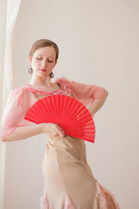 Young woman standing against red background