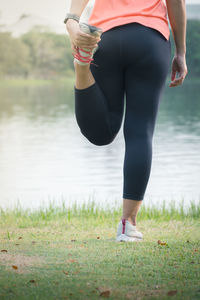 Low section of woman standing by lake