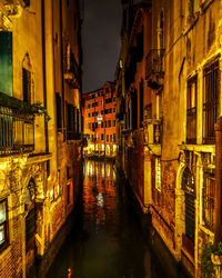 Canal amidst buildings in city at night