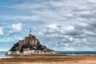 Scenic view of mont saint-michel against cloudy sky