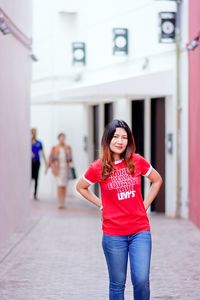 Portrait of woman standing against red wall