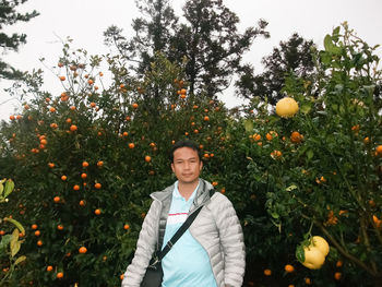 Portrait of man standing against orange tree