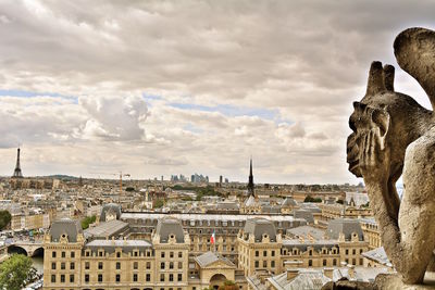 Statue in city against cloudy sky