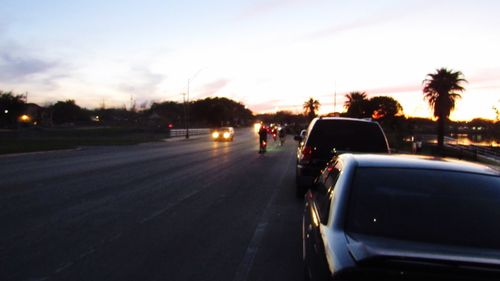 Cars on road against sky during sunset