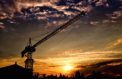 Low angle view of silhouette cranes against sky during sunset