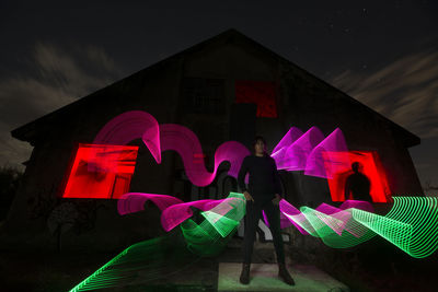 Young woman standing against light painting at night