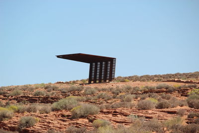 Lifeguard hut on field against clear blue sky