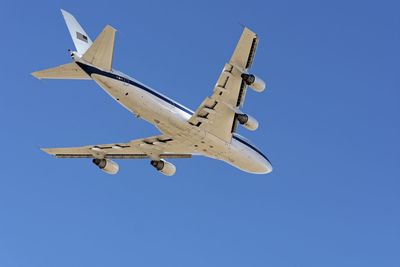 Low angle view of airplane flying against clear blue sky