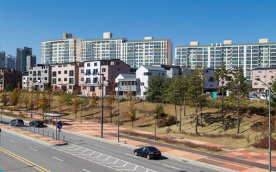 Cars on road by buildings against clear sky