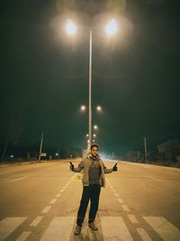 Full length portrait of man standing on street at night