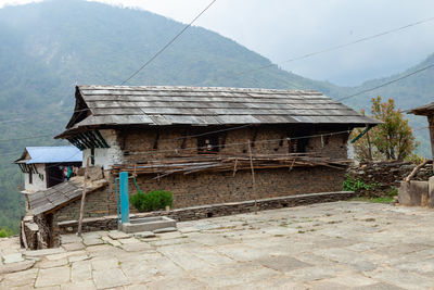 Abandoned house by mountain against sky