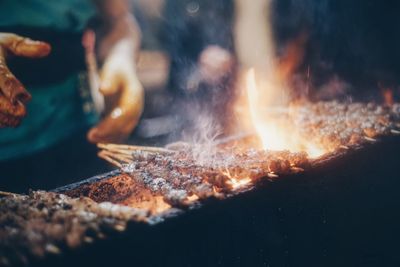 Cropped person preparing meat on skewers