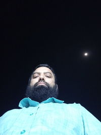 Low angle portrait of man against sky at night