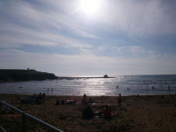 People on beach against sky during sunset