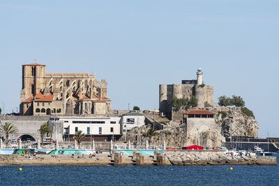 Buildings by river against clear sky