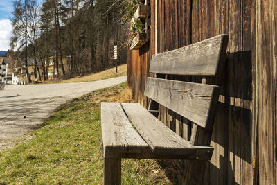 Empty bench on footpath by trees on field