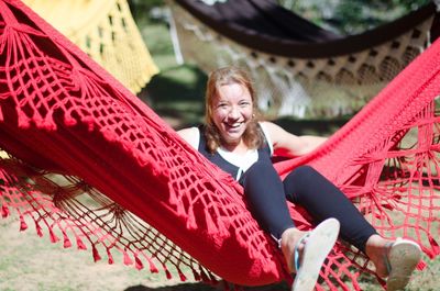Cheerful woman sitting on hammock during sunny day