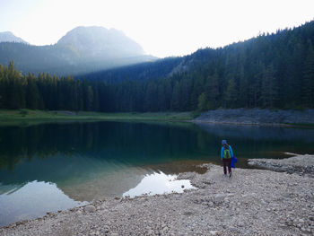 Man standing by lake against mountains