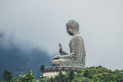 Statue of buddha on mountain against sky