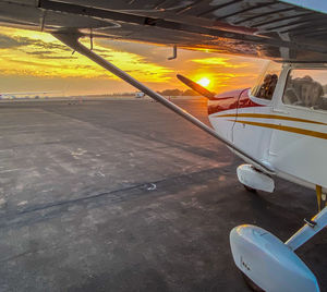 Airplane on runway against sky during sunset