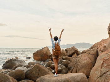 Rear view of man standing on rock at beach