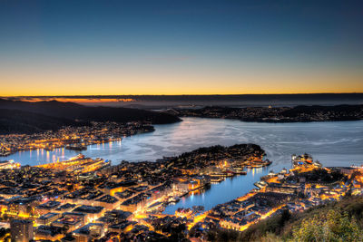 High angle view of buildings by lake against clear sky during sunset