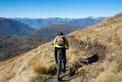 Rear view of man riding bicycle on mountain