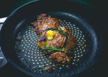 Beef steak with rosemary, garlic, salt and pepper inside iron skillet