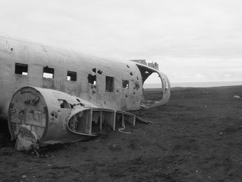 Abandoned airplane on beach against sky