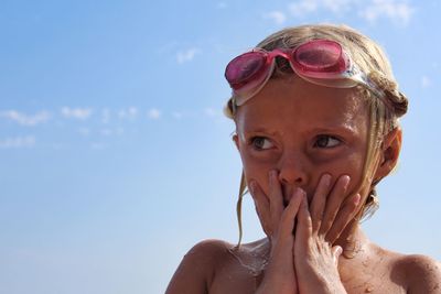 Close-up of wet girl standing against sky