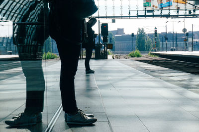 Low section of man standing on sidewalk in city