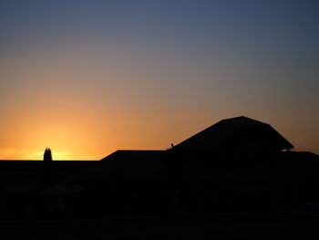 Silhouette buildings against clear sky at sunset