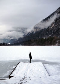 Man standing on frozen lake against mountain