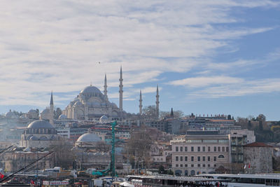 Mosque in city against sky