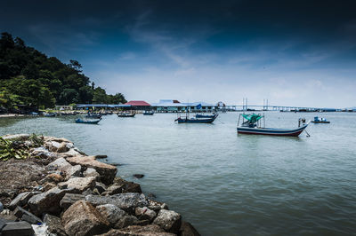 Fishing boats moored in sea against sky